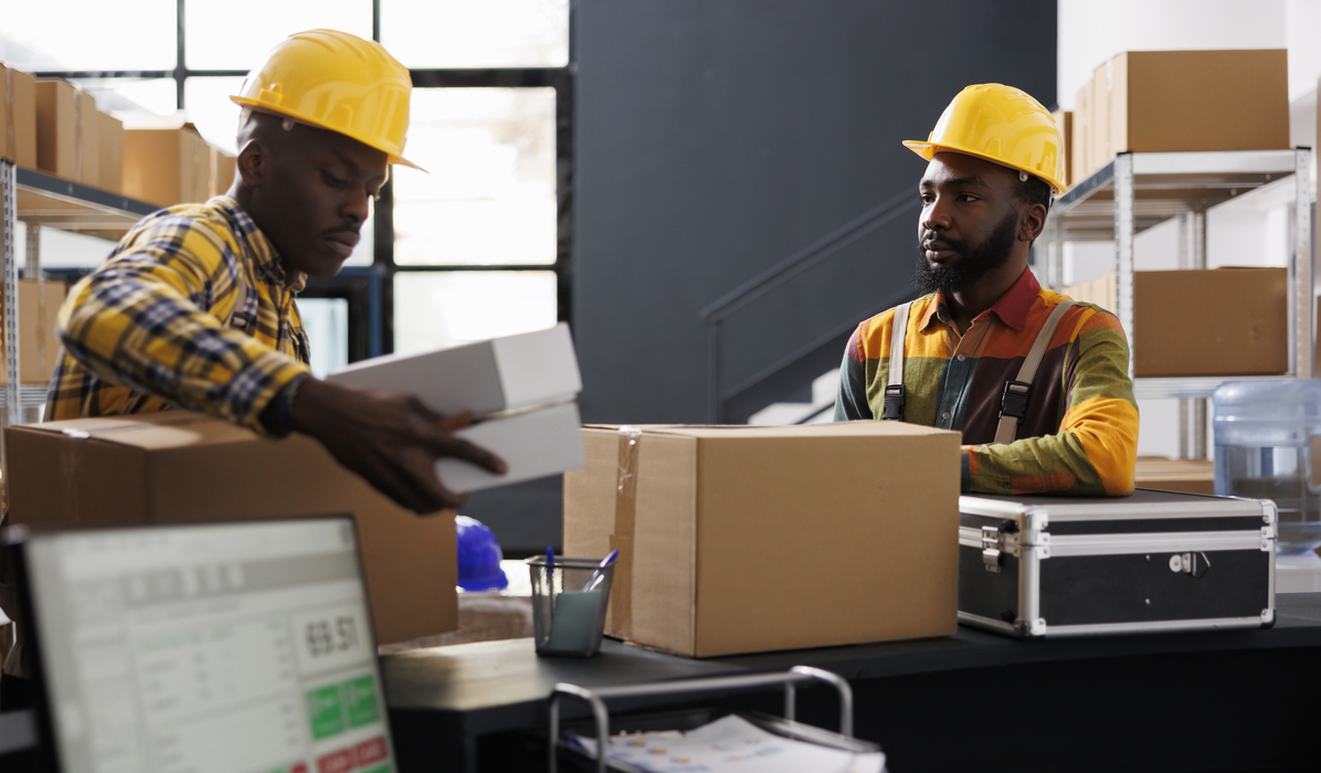 Warehouse employees putting packed boxes on counter desk ready for shipment. African american e commerce retail storehouse managers preparing customer packages for transportation